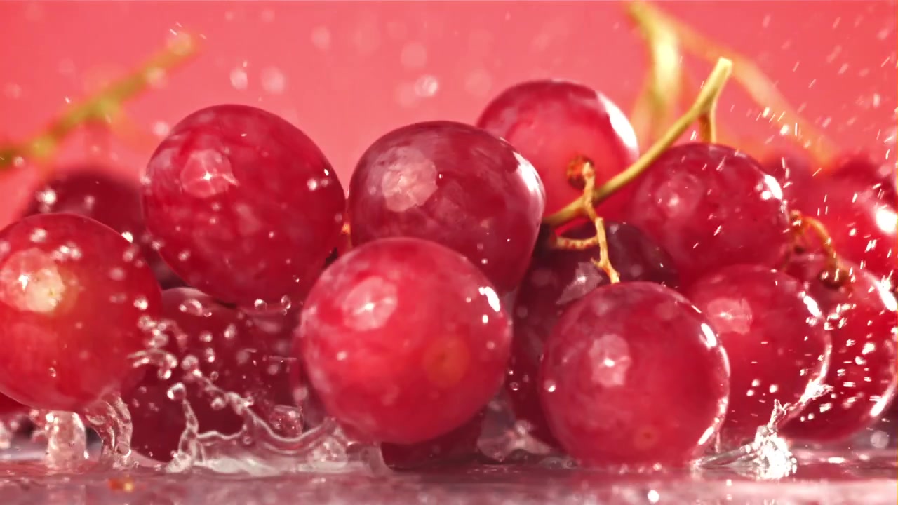 Uva rossa fresca che cade nell'acqua con schizzi al rallentatore