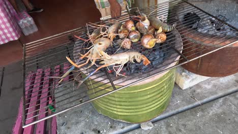 shrimp and seashells cooking over charcoal flames.