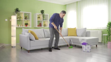 hombre de mediana edad haciendo tareas domésticas, limpiando pisos en la sala de estar.