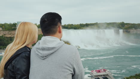 a young chinese guy with his caucasian girlfriend is having a nice weekend at niagara falls enjoying
