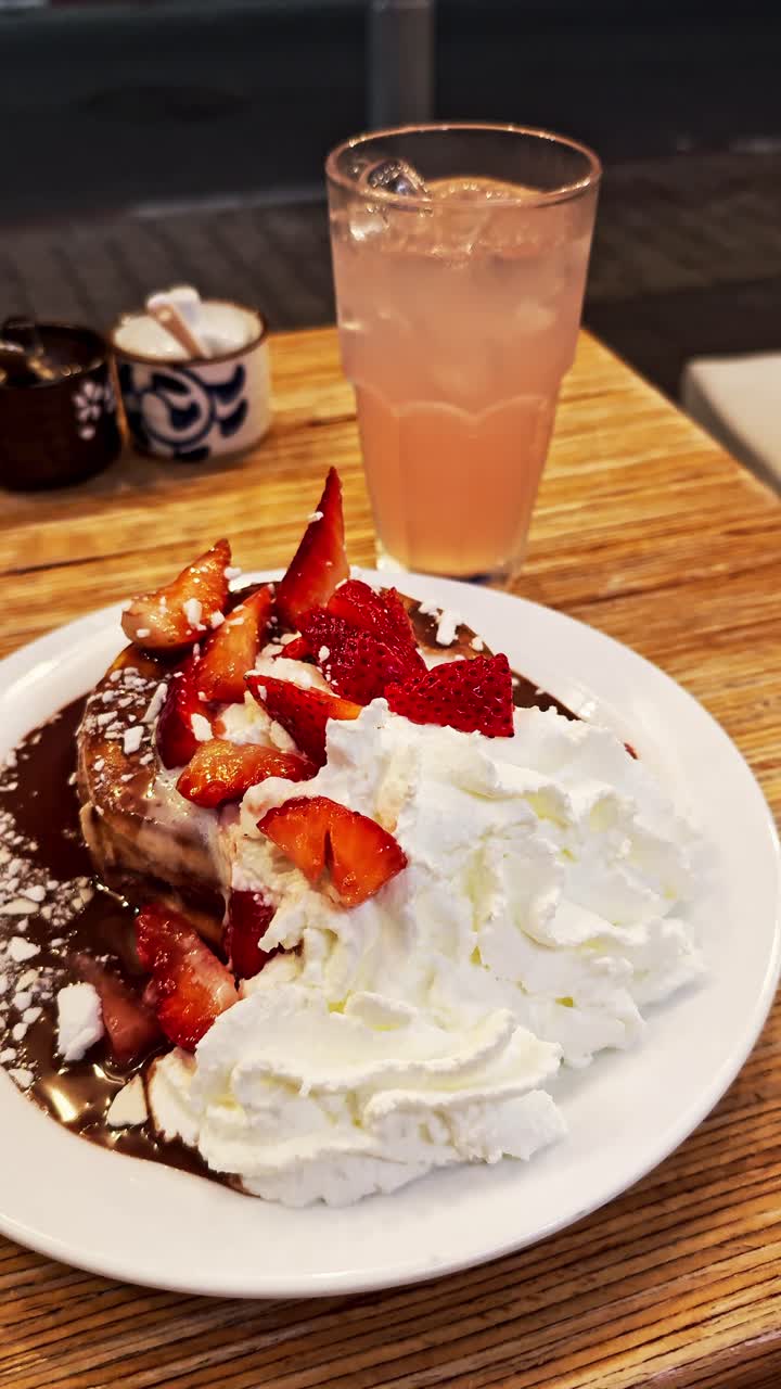 Pancake con fragole, panna montata e salsa al cioccolato.