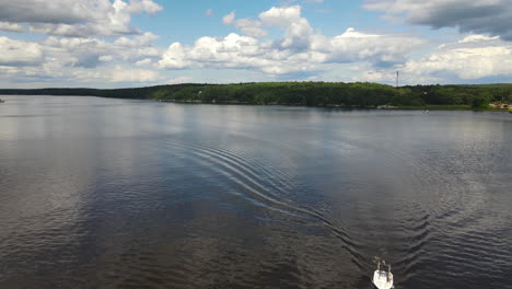 Drone-flyover-shot-of-a-slow-moving-boat-on-a-river,-wide-expanse