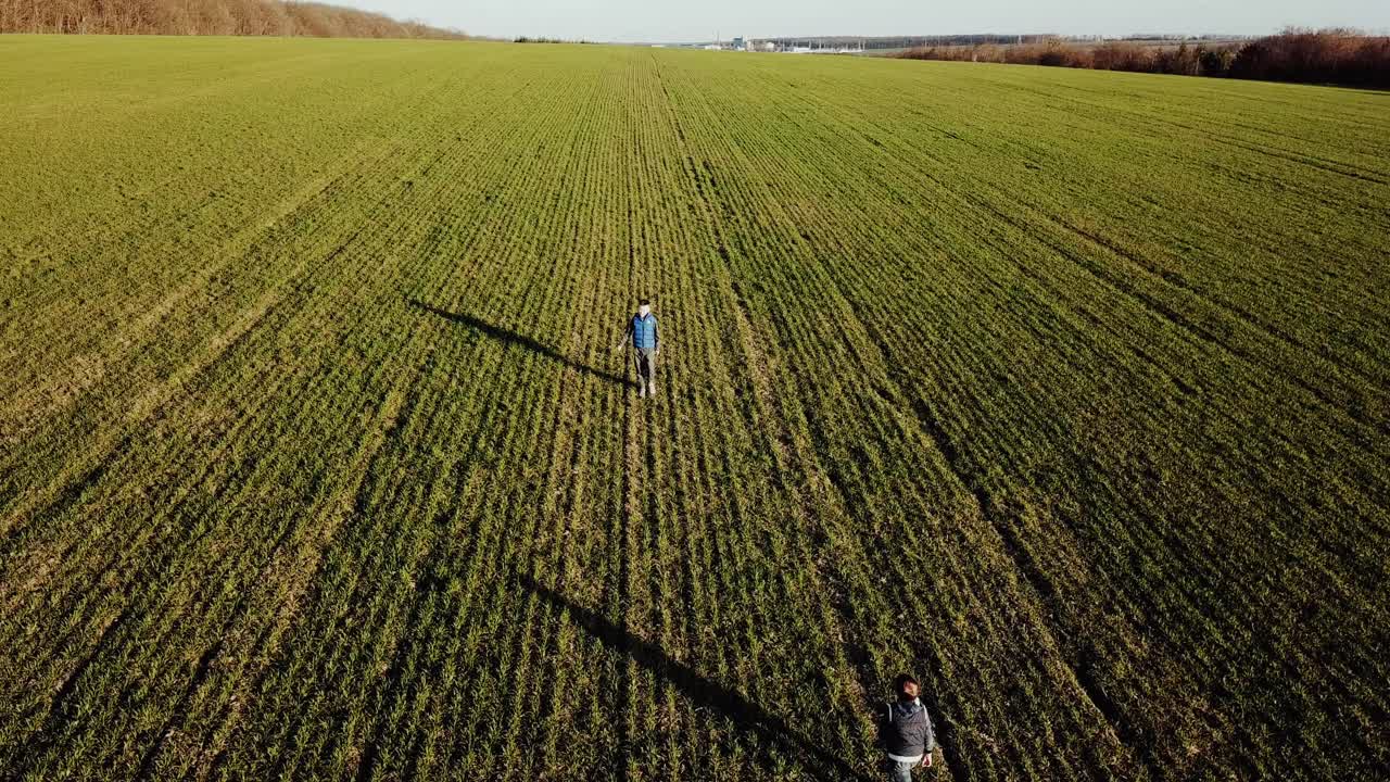 Aerial view young brothers running through a green grassy field with smiles on their faces