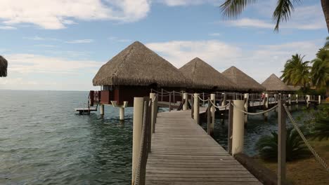 lovey tahitian tourist cottages on the sea with wooden bridge to them