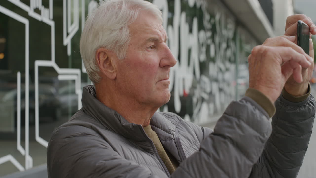 스마트폰을 사용하는 중년 남자의 초상화 도시에서 관광 사진을 찍고 휴대폰 카메라로 사진을 찍고 있습니다.