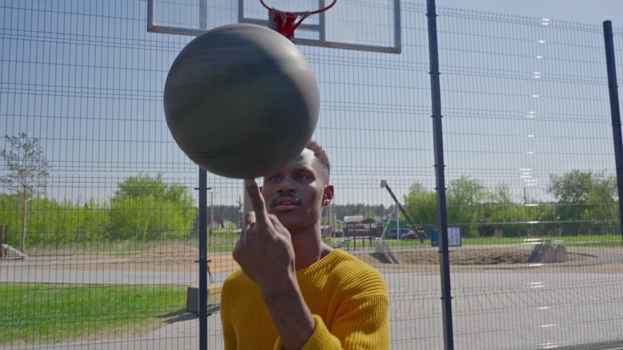 Young Black Man Spinning a Basketball on His Finger on an Outdoor Court