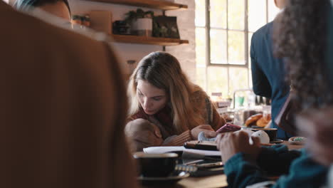 young mother caring for baby in cafe nurturing sleeping child in busy restaurant enjoying motherhood