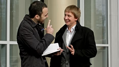 two businessmen meeting outside of office building, smiling