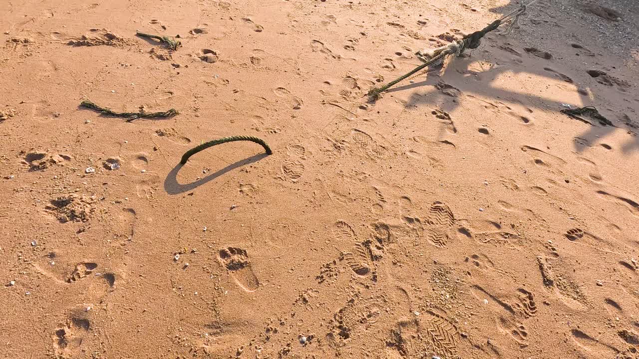 태국 춘부리 (chonburi) 의 모래 해변에 있는 발자국과 그림자. 자연 조명은 모래의 질감과 패턴을 강조합니다.