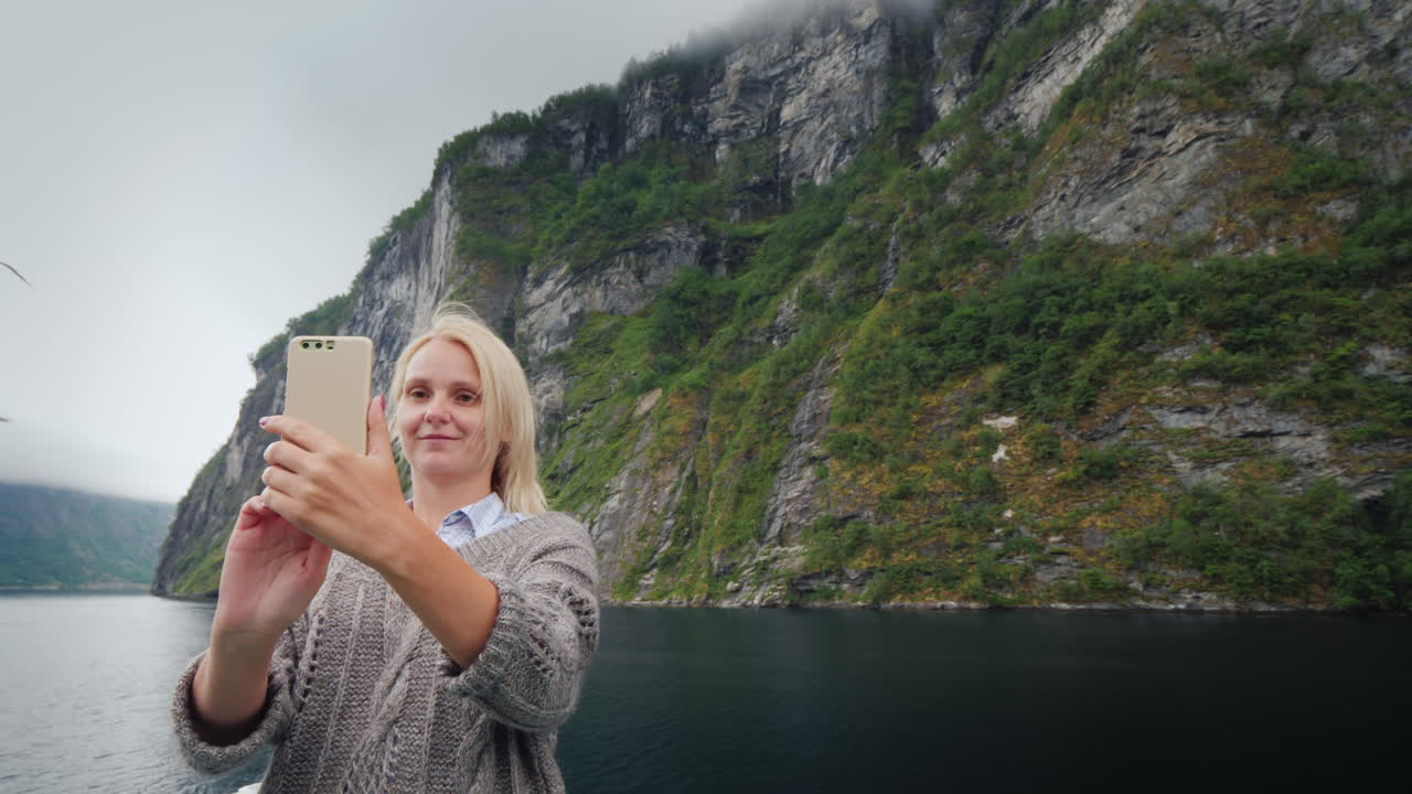 una mujer se toma fotos con el fondo del fiordo noruego viajando en un crucero