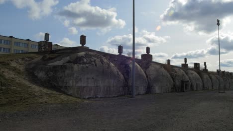 the exterior of the concrete bomb shelter to hide civil people, an underground apocalypse bunker built in old coastal fortification, cloudy spring day, wide handheld shot