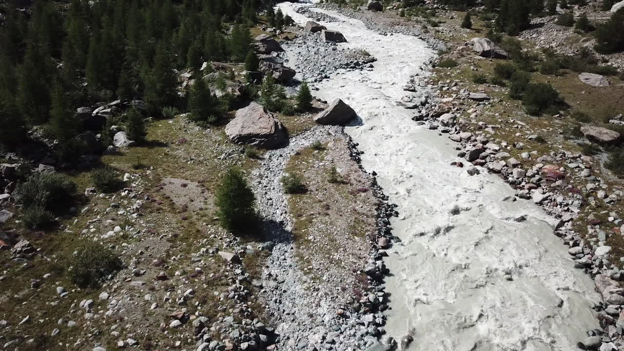 vista de drones, inclinación hacia arriba de un río rocoso y fangoso de los alpes suizos con fuerte corriente, valle de montaña