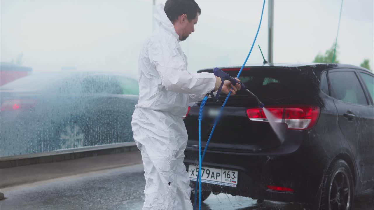 Man washing a black car at a self-service car wash