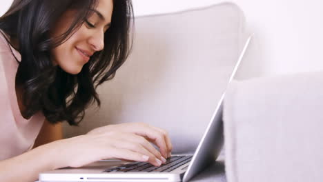 Woman-lying-on-a-sofa-using-her-laptop