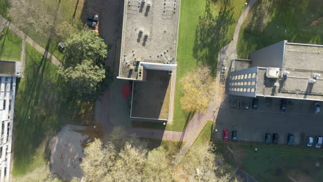 top down aerial of apartment building rooftop with green parks in autumn