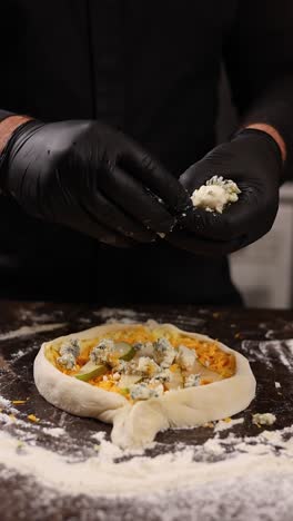 el chef añadiendo queso azul y cubiertos de pera a la pizza