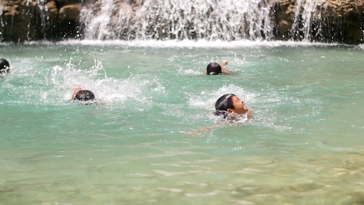 Kids Swimming at a Waterfall
