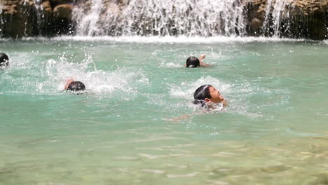 kids swimming at a waterfall