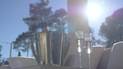 champagne and glasses on terrace table with sun in the background