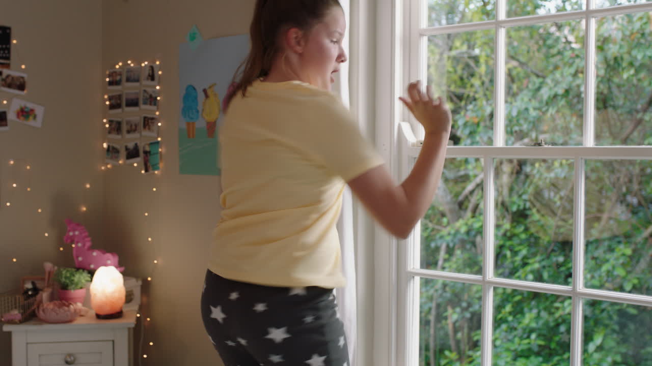 행복한 십대 소녀는 침실에서 춤을 추고 재미있는 춤을 추고 주말을 축하하고 긍정적인 느낌으로 집에서 잠옷을 입고 있습니다.