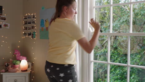 una adolescente feliz bailando en el dormitorio divirtiéndose bailando celebrando el fin de semana sintiéndose positiva usando pijama en casa