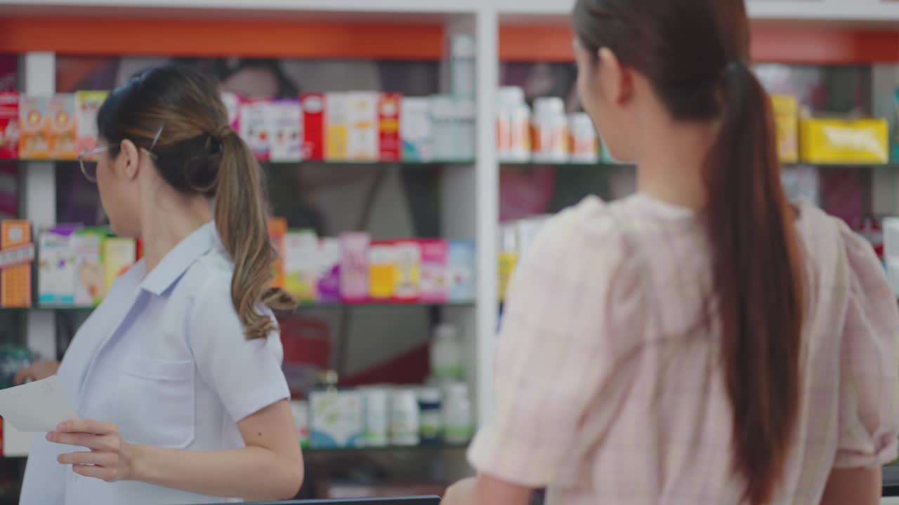 아시아 여성 약사가 고객에게 처방전 약을 판매하고 있습니다.