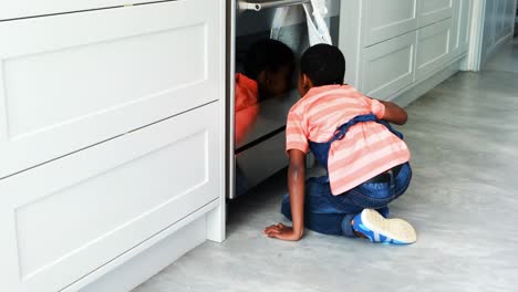 curious boy peeking in the oven and calling his father