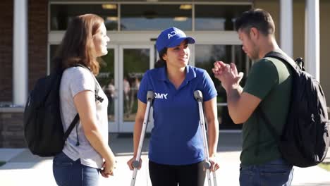 young woman in crutches engages with friends outside building, demonstrating resilience and connection while navigating mobility challenges