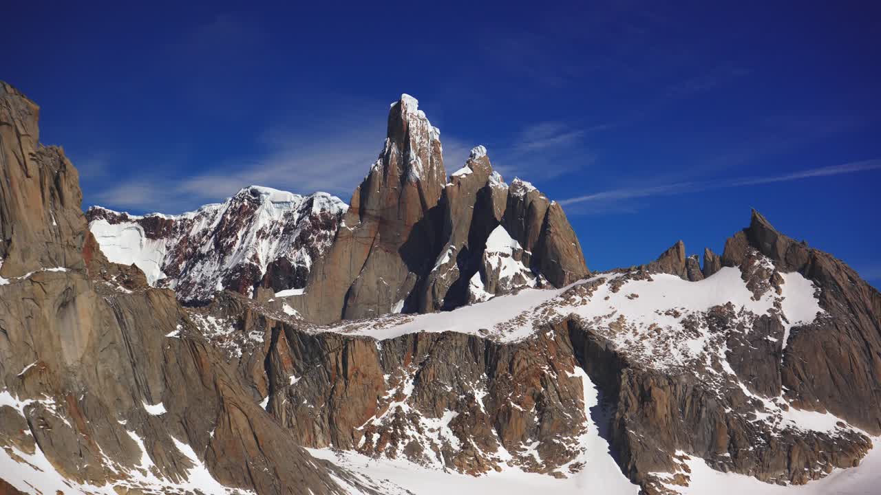 Time-lapse of Cerro Torre and its rugged granite spires rising dramatically above snowy ridges on a clear day in Los Glaciares National Park, El Chaltén, Patagonia, Argentina