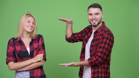 young happy couple snapping fingers and showing something together