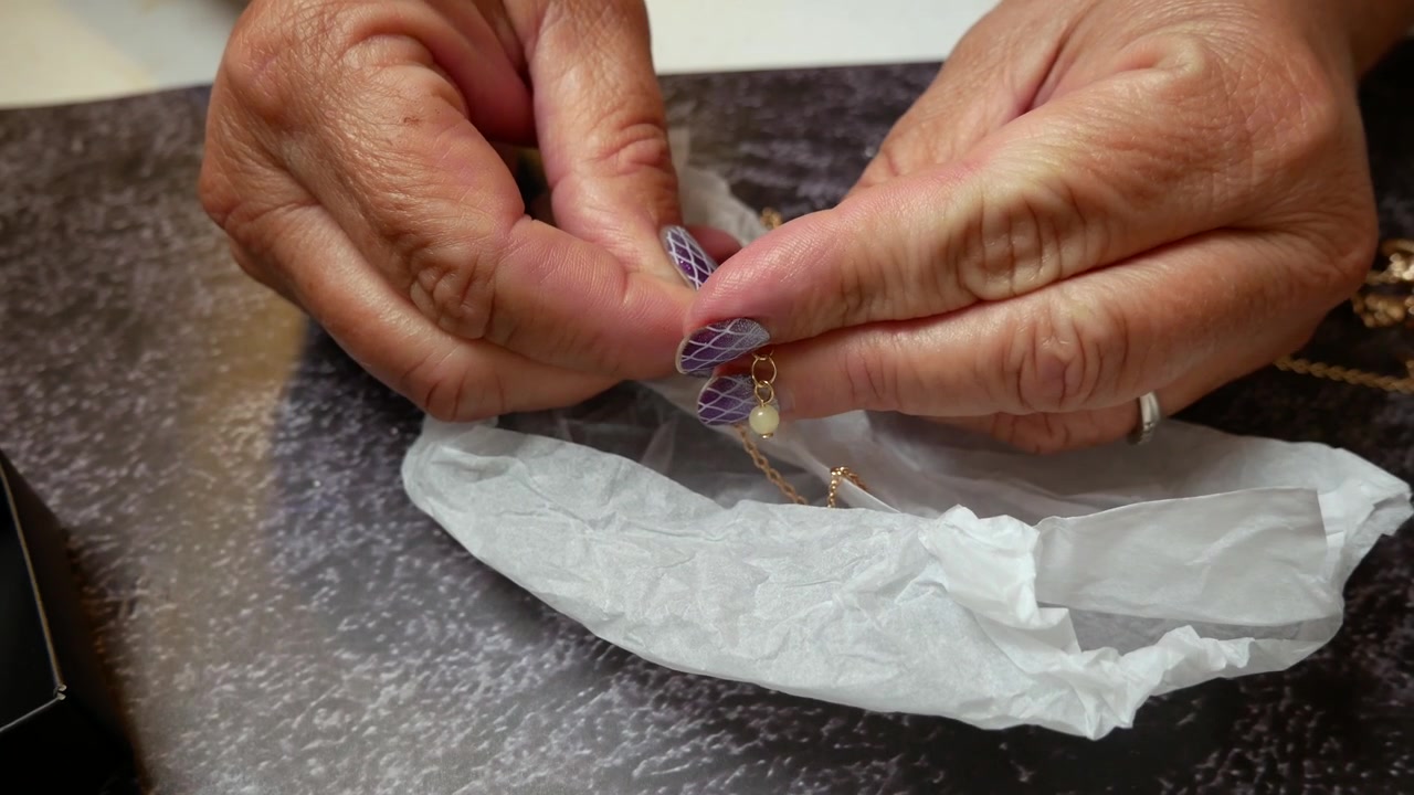 Primo piano delle mani di una donna che allacciano una catena di collana