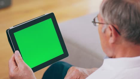 un abuelo usa una tableta con una pantalla verde