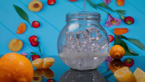 vista macro de una jarra con hielo y agua que se vierte en el fondo de la fruta