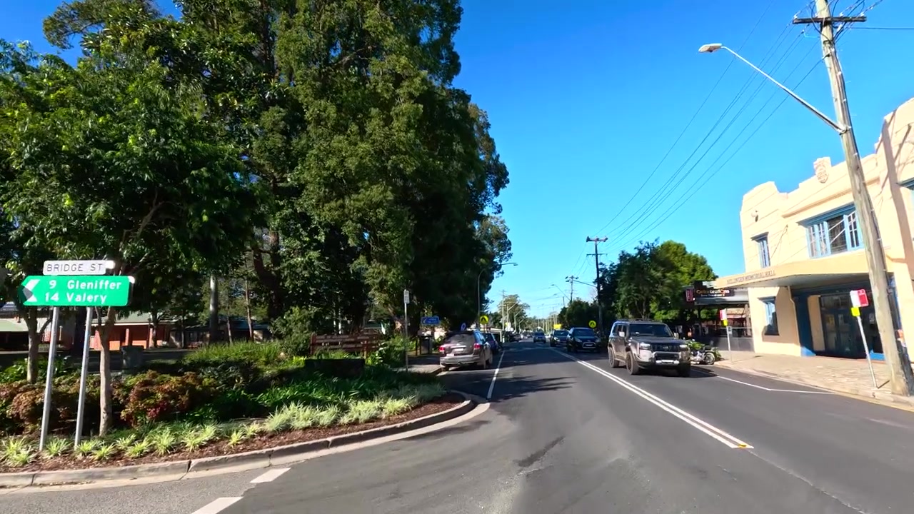 Una familia camina junto a casas residenciales y una oficina de correos bajo un cielo soleado y brillante.