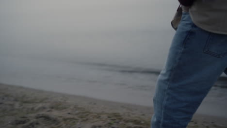 unrecognizable man walking sea beach. guy holding hands in jeans pockets closeup