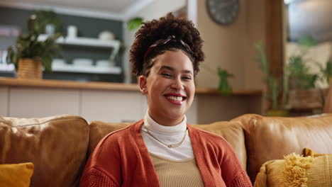 a young woman smiles happily as she sits on a couch in her living room.