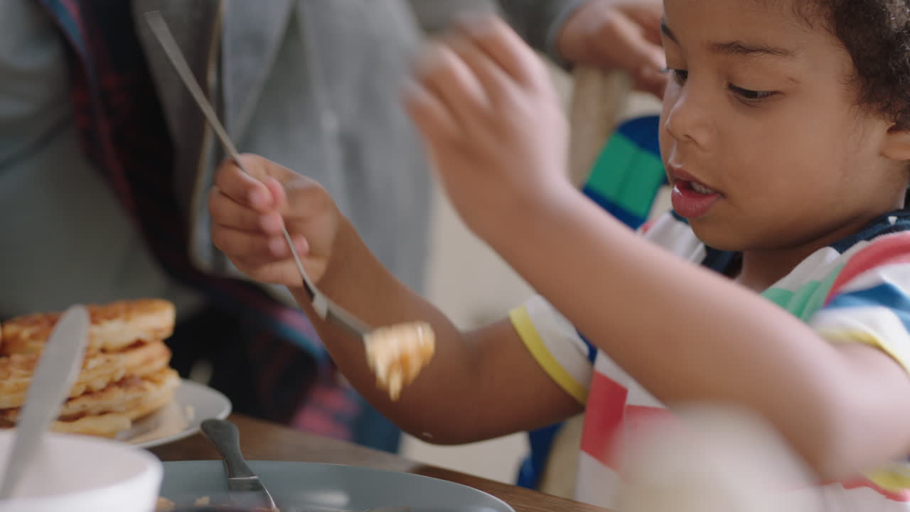 niño feliz comiendo gofres frescos para el desayuno con su padre disfrutando de un delicioso dulce casero en la cocina en casa