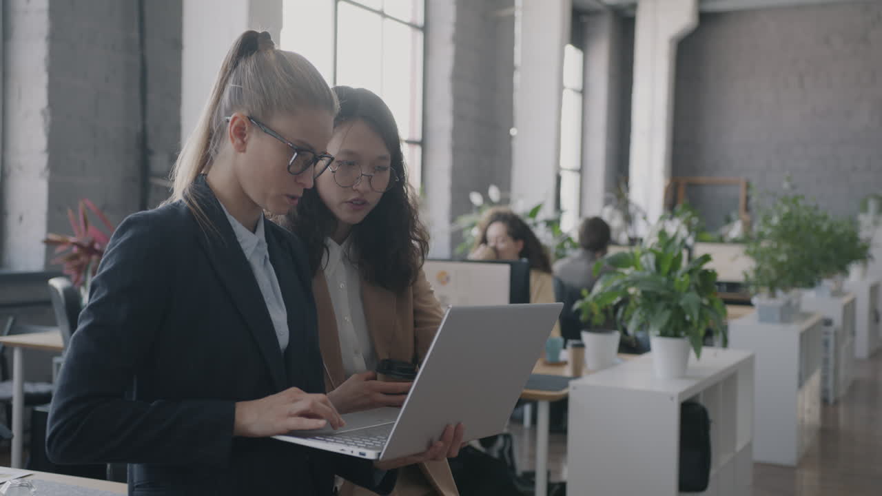 Businesswomen Collaborating on a Laptop in a Modern Office