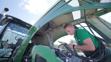 farmer mechanic repairing tractor. open tractor hood, engine. repair agricultural technology