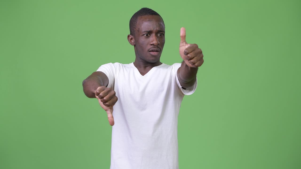 joven africano confundido eligiendo entre pulgares arriba y pulgares abajo