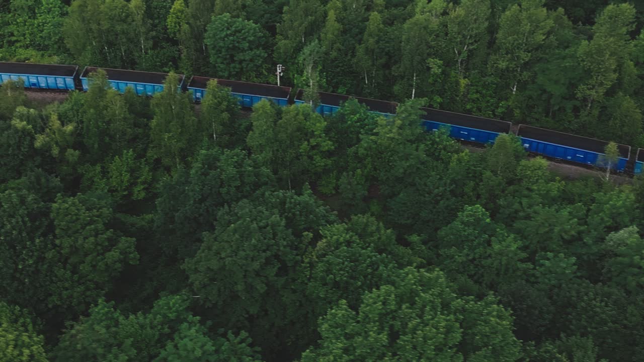 Coal train wagons in green forests of mining area AERIAL View