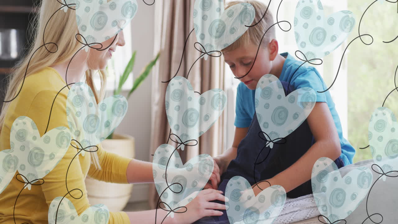 анимация сердечных воздушных шаров над счастливой кавказской матерью, связывающей обувь своему сыну дома