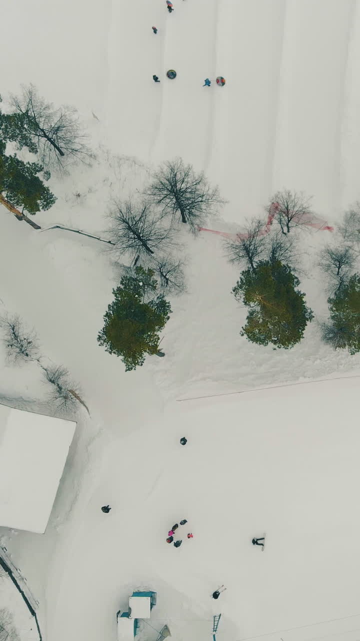 aerial motion over pictorial ski resort with lift top station and people sliding on comfortable snowy trails