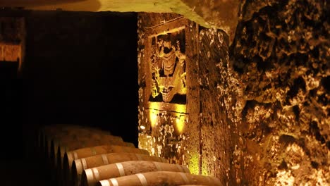 dimly lit cellar with stacked wine barrels