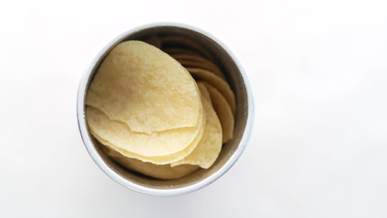 Hand taking a potato chip from a container