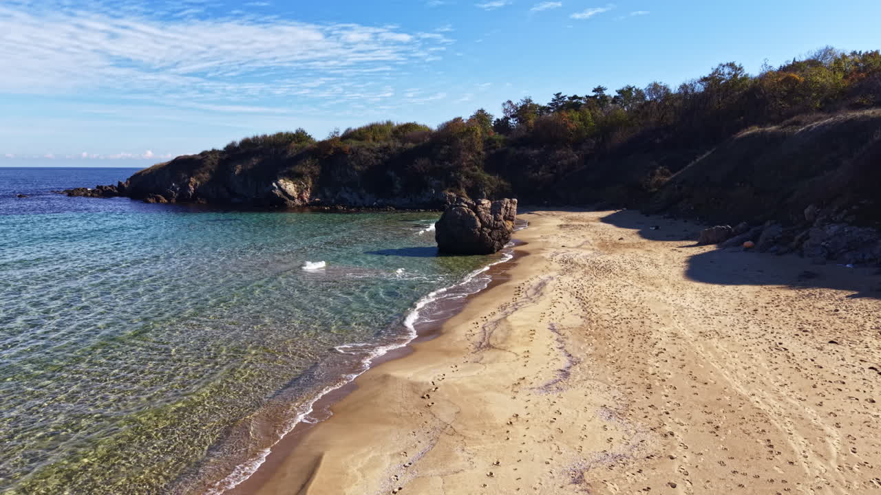Costa tranquilla con acque limpide e sabbia dorata sotto un cielo azzurro brillante
