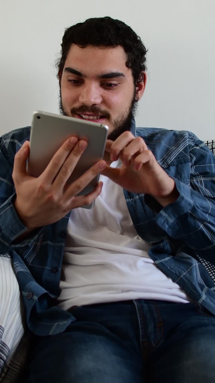 Young man expressing different emotions while using tablet