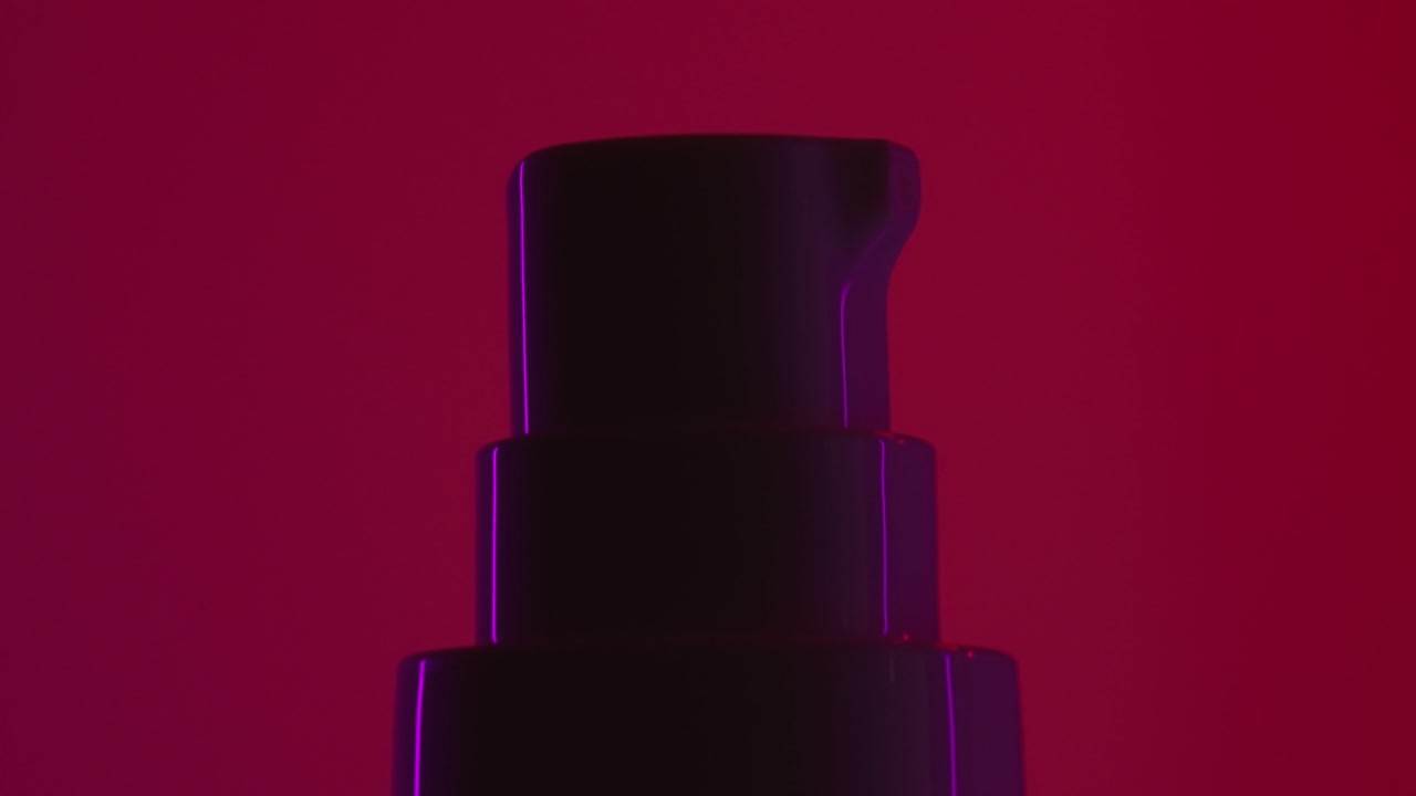 bote dosificador de crema cosmética girando sobre fondo rojo