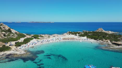 boats and tourists swim and relax at punta molentis beach, villasimius, sardinia - aerial 4k