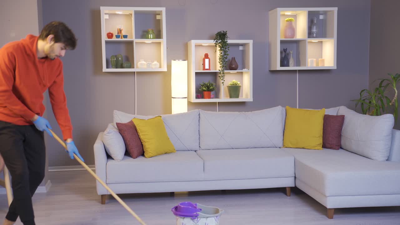 집을 청소하는 쾌활한 젊은이가 춤을 추고 있습니다.